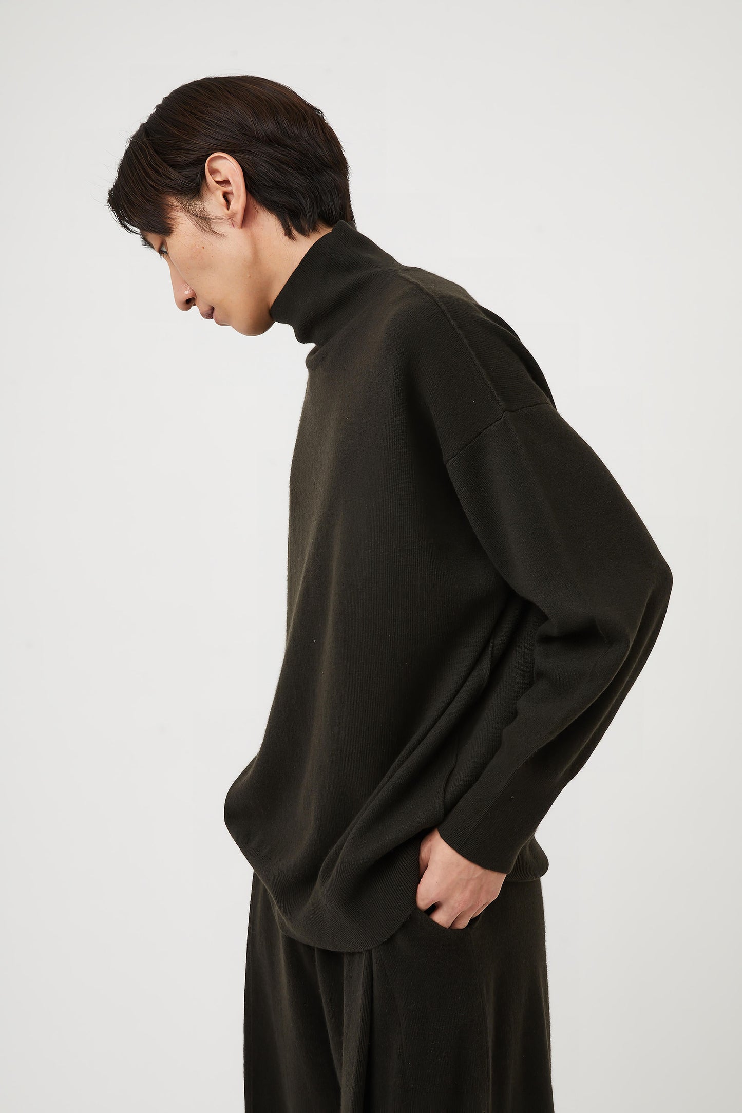 This image features the Kotto Sweater, characterized by its high-neck design and relaxed fit. The sweater is crafted from a classic jersey knit, showcased in a soft, forest color.