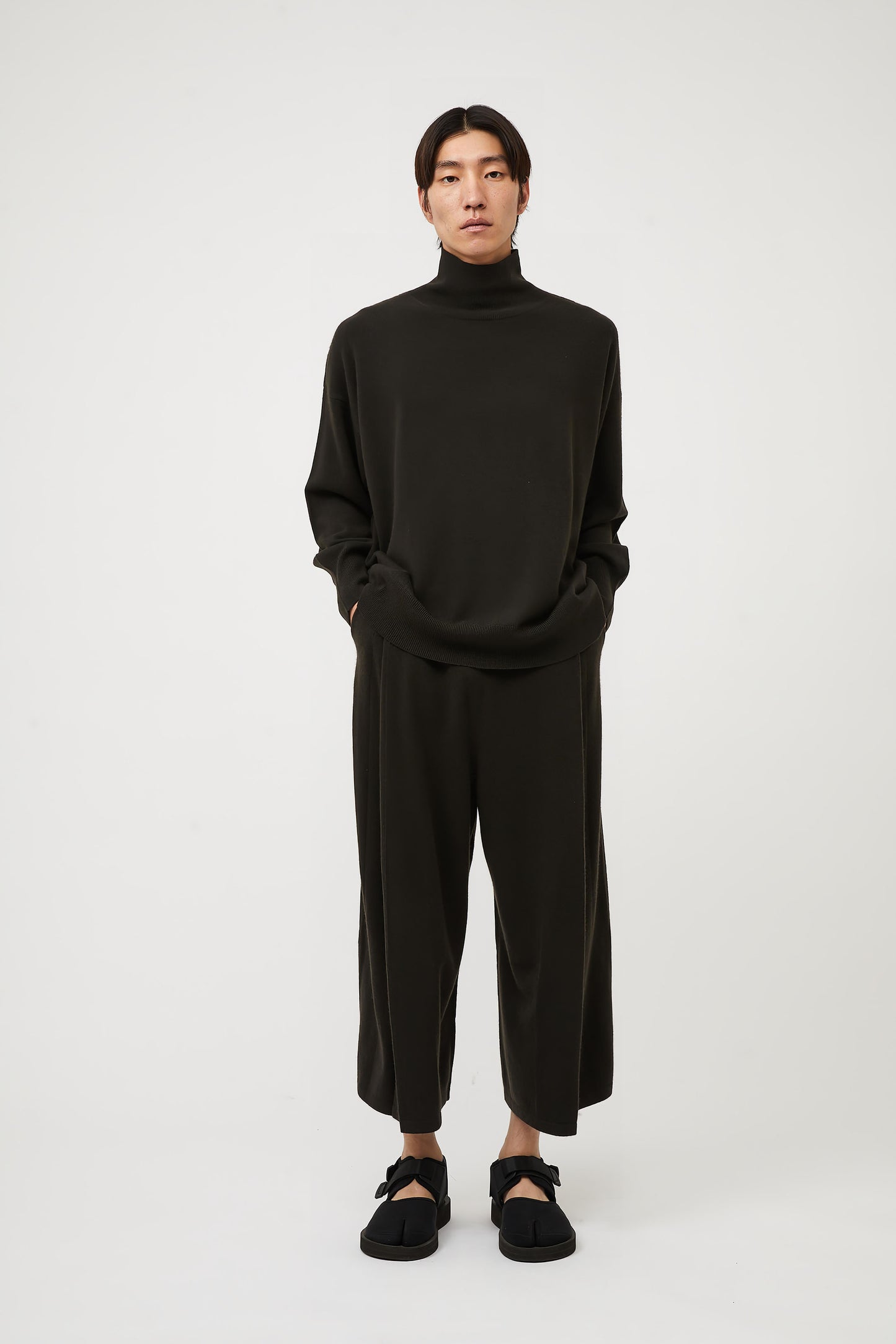 This image features the Kotto Sweater, characterized by its high-neck design and relaxed fit. The sweater is crafted from a classic jersey knit, showcased in a soft, forest color.