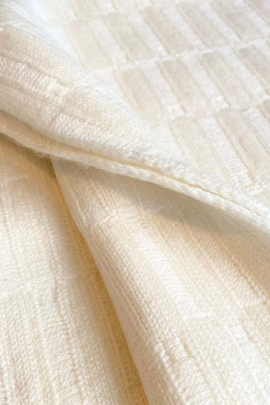 The Lake throw in Ivory, displayed on a chair with a neutral background