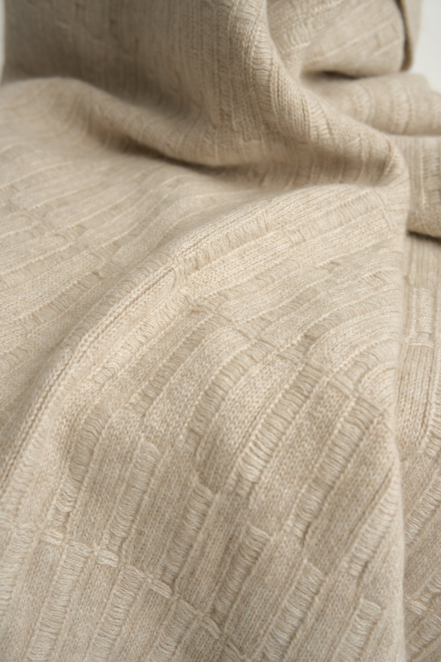 A feather throw blanket made of linen, draped over the back of a chair against a white background.