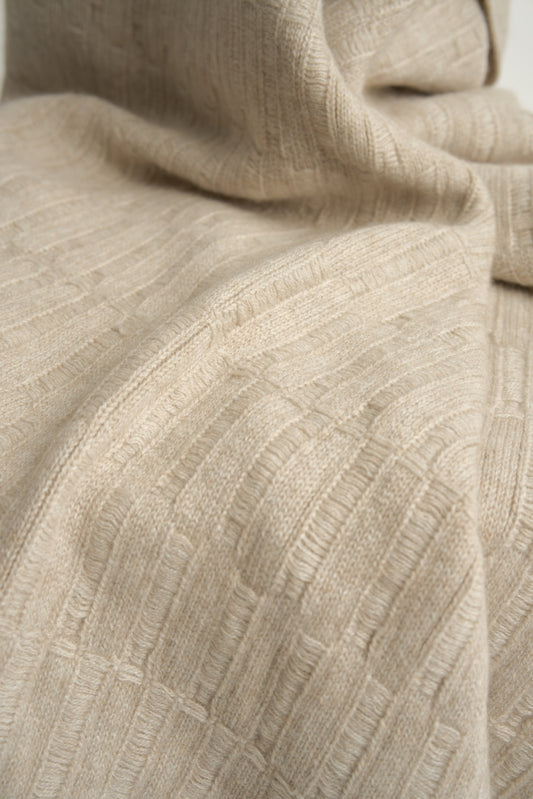 A feather throw blanket made of linen, draped over the back of a chair against a white background.