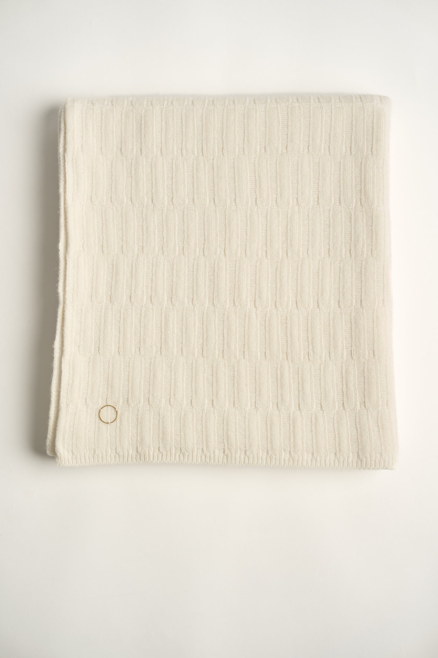 A folded ivory-colored throw blanket with a subtle textured pattern displayed on a white background.