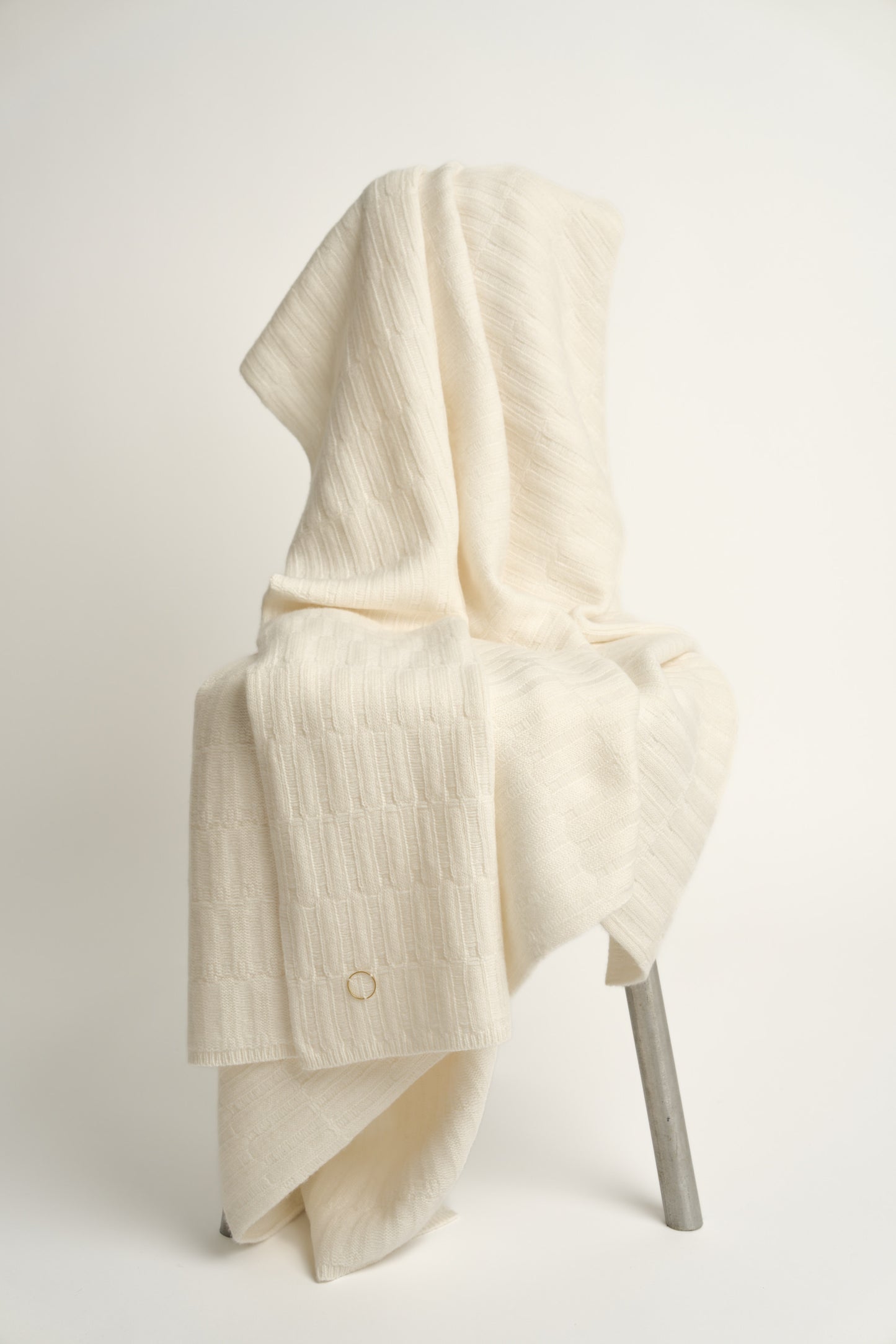 The Lake throw in Ivory, displayed on a chair with a neutral background