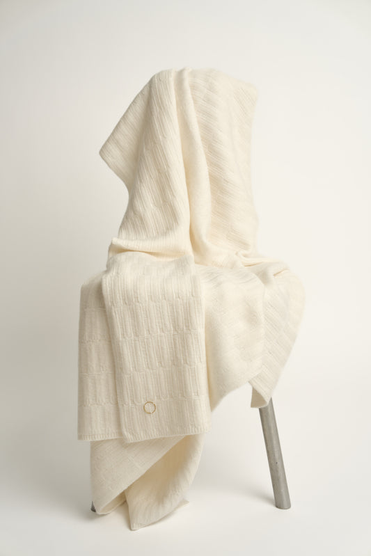 The Lake throw in Ivory, displayed on a chair with a neutral background