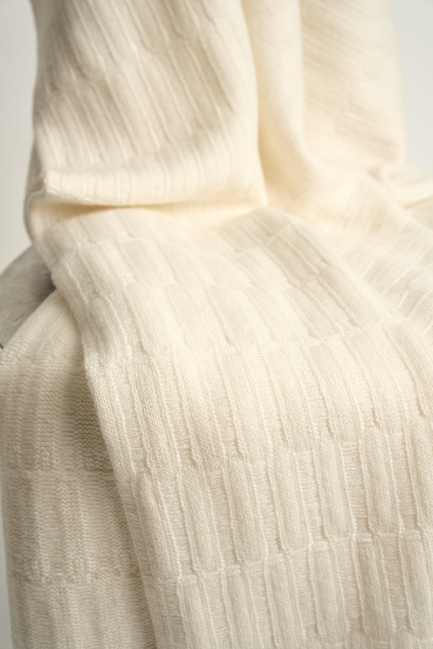 The Lake throw in Ivory, displayed on a chair with a neutral background