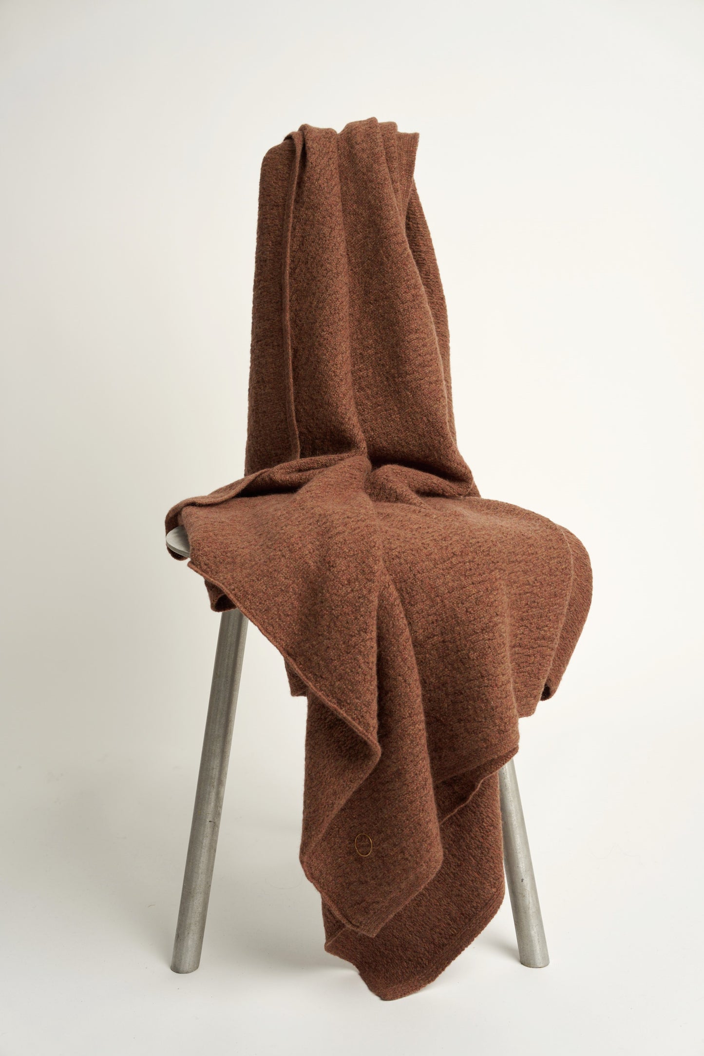 A brown coloured soft throw draped over a chair
