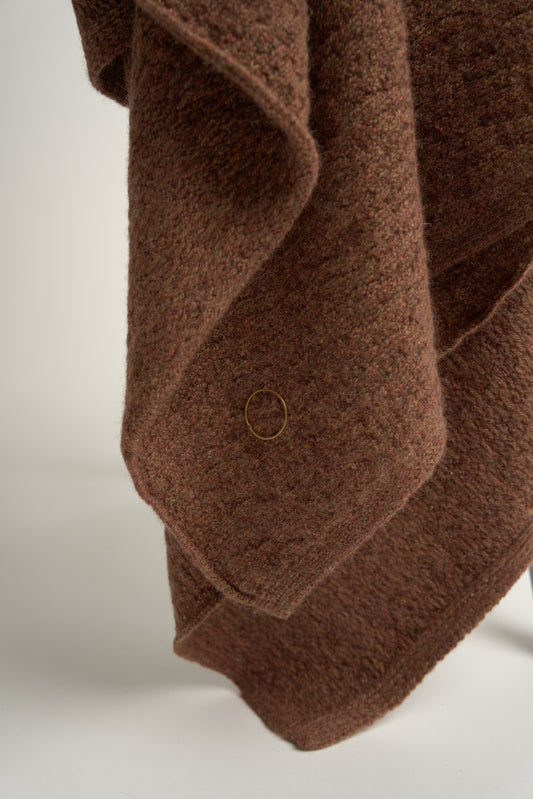 A brown coloured soft throw draped over a chair