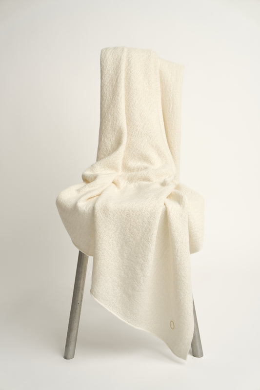 A luxurious and elegant ivory coloured throw draped over a chair