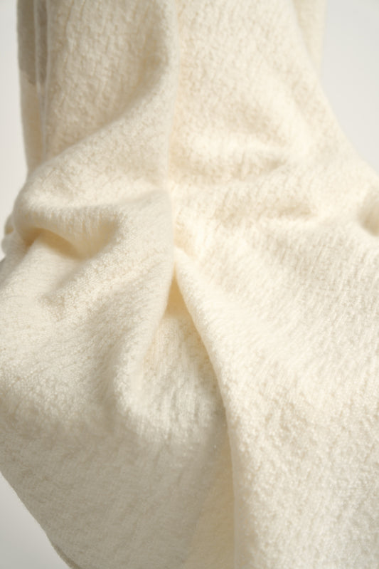 A luxurious and elegant ivory coloured throw draped over a chair