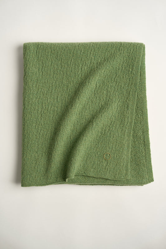A folded green coloured soft throw.