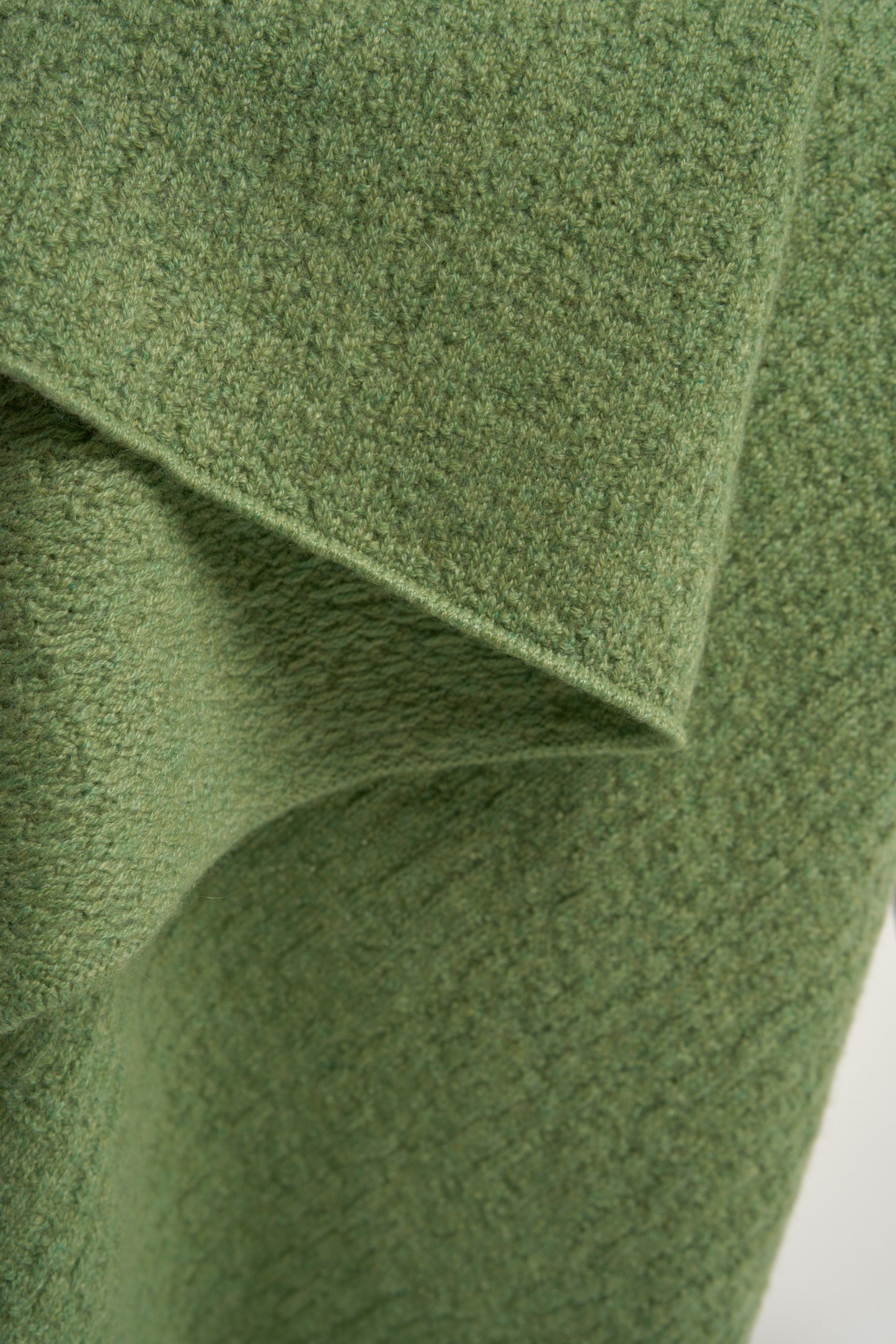 A green coloured soft throw draped over a chair