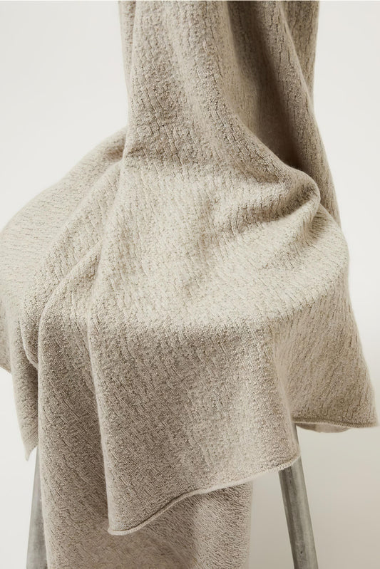 A luxurious and elegant feather coloured throw draped over a chair