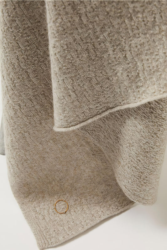 A luxurious and elegant feather coloured throw draped over a chair