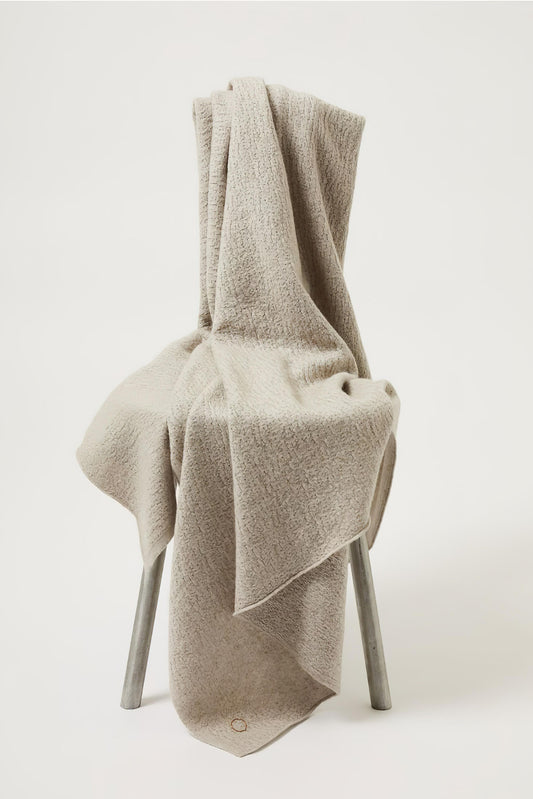 A luxurious and elegant feather coloured throw draped over a chair