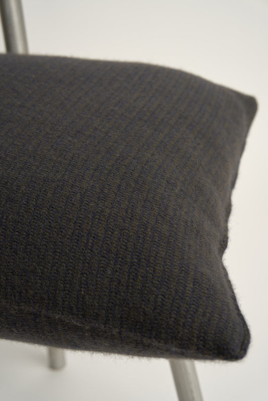 This image displays the Letra Cushion Cover, characterized by its knitted two-tone float knit design. The cushion cover features a textured, cozy appearance in a dark color, which comes across as modern and stylish.