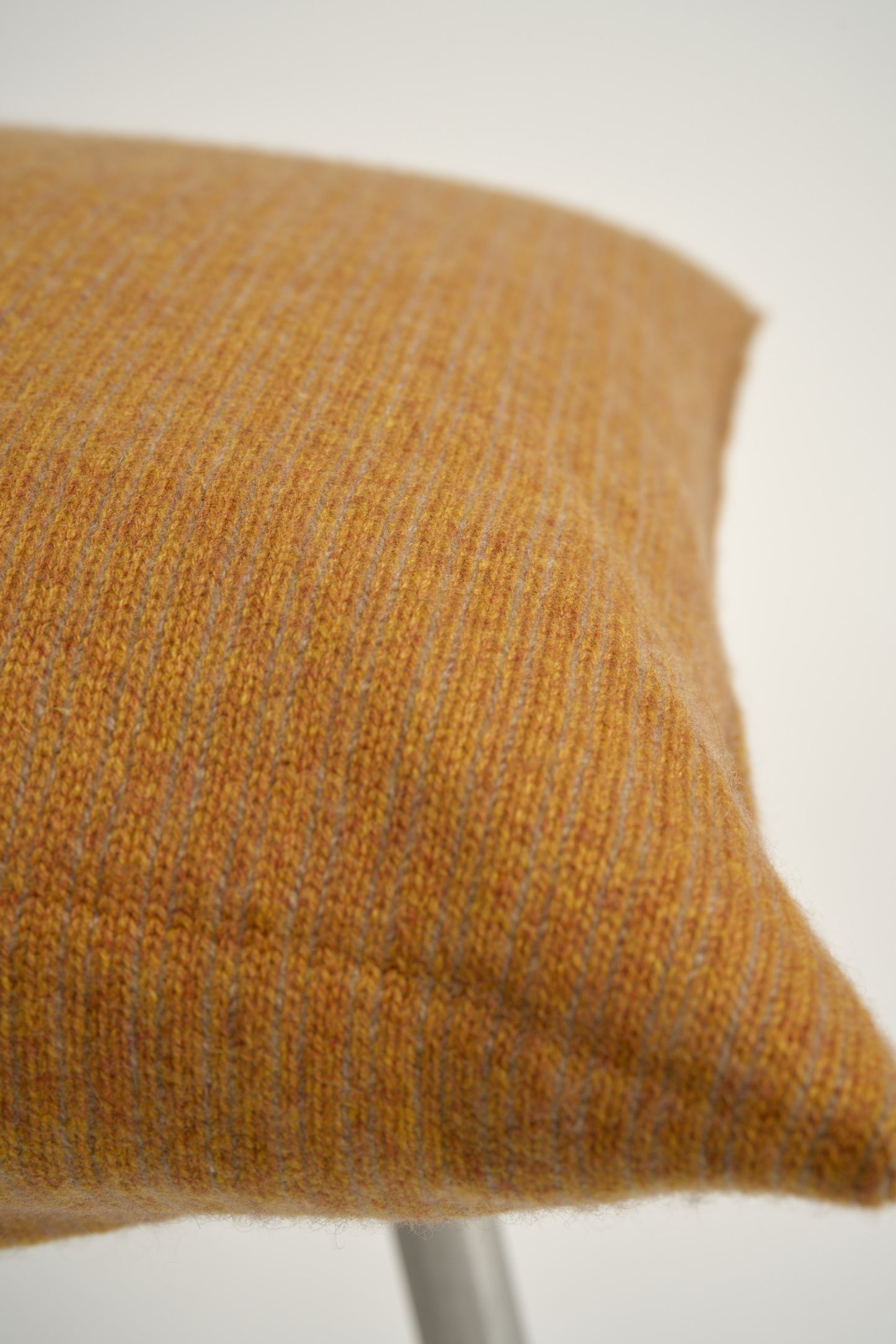 This image displays the Letra Cushion Cover, characterized by its knitted two-tone float knit design. The cushion cover features a textured, cozy appearance in a honey & taupe color, which comes across as modern and stylish.