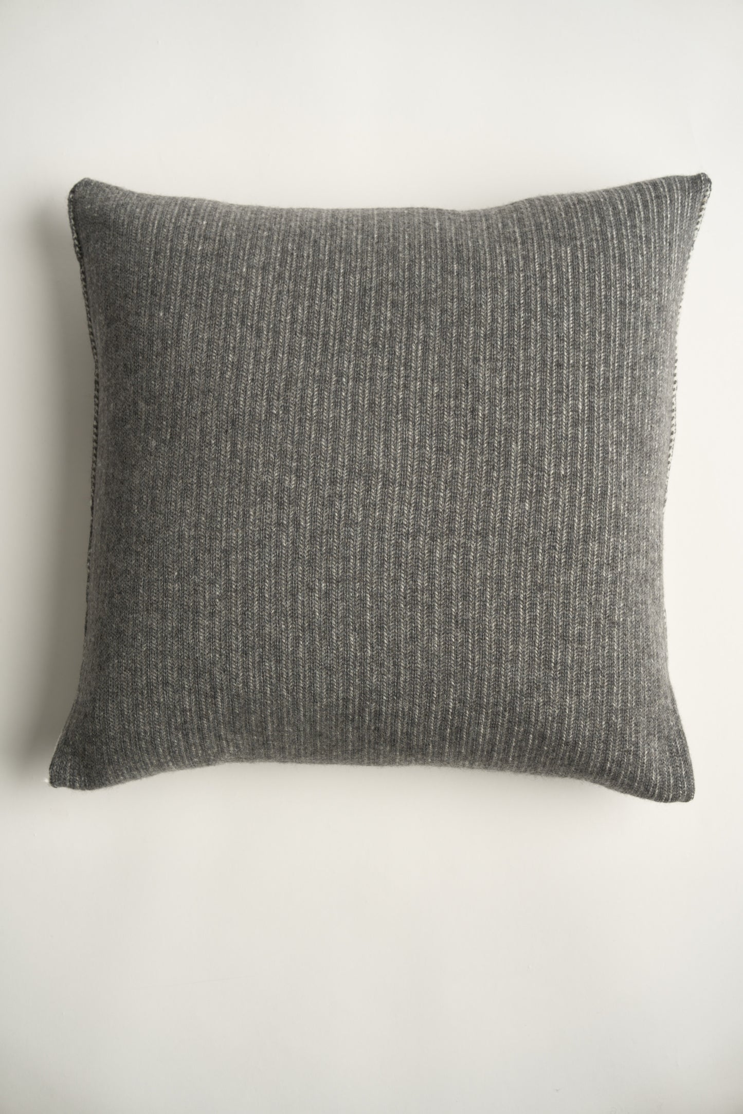 This image displays the Letra Cushion Cover, characterized by its knitted two-tone float knit design. The cushion cover features a textured, cozy appearance in an ivory & slate color, which comes across as modern and stylish.