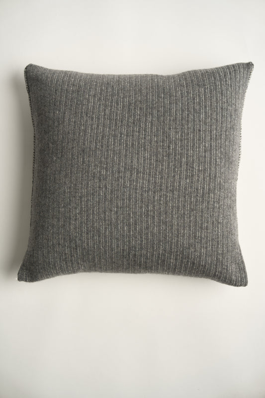 This image displays the Letra Cushion Cover, characterized by its knitted two-tone float knit design. The cushion cover features a textured, cozy appearance in an ivory & slate color, which comes across as modern and stylish.