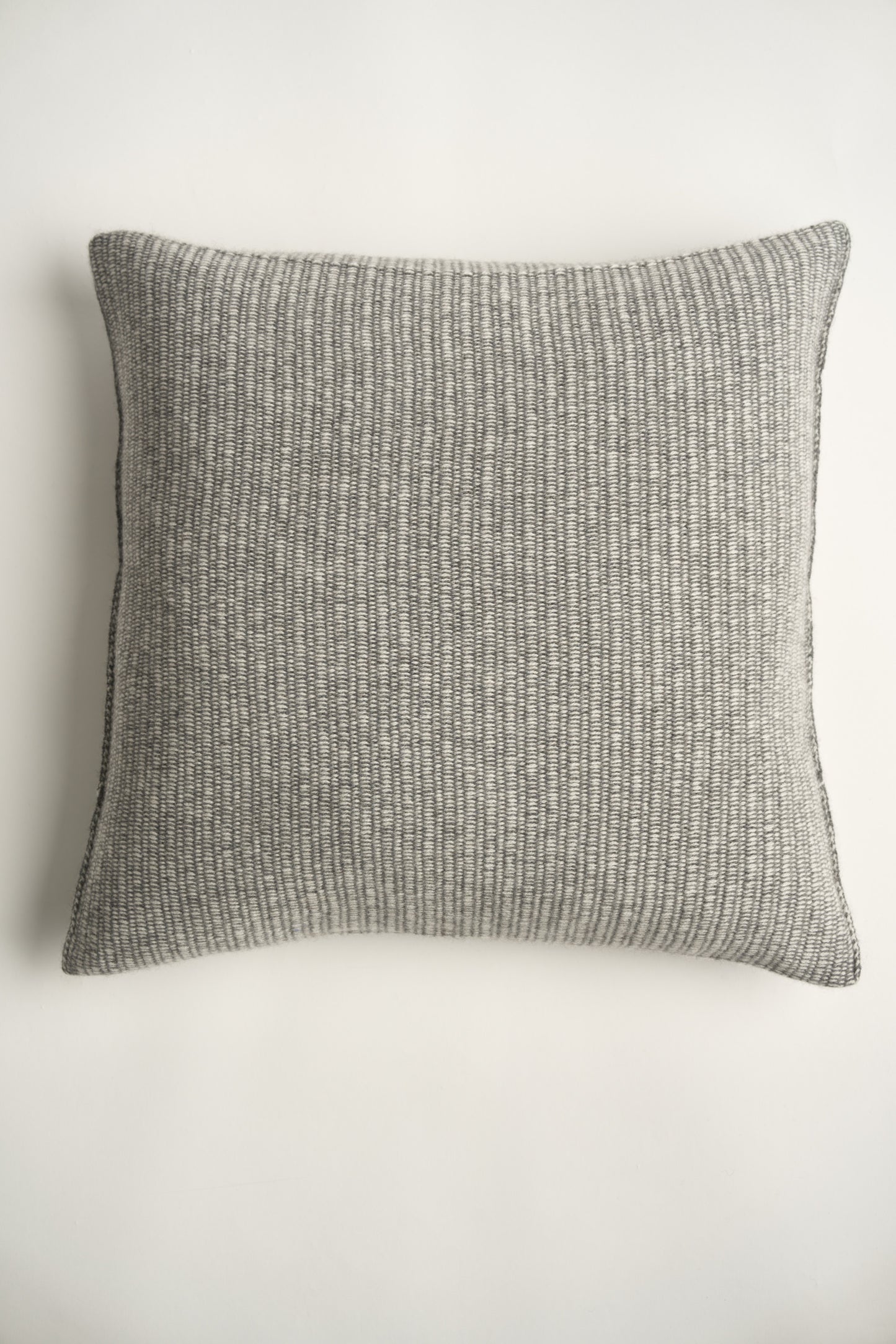 This image displays the Letra Cushion Cover, characterized by its knitted two-tone float knit design. The cushion cover features a textured, cozy appearance in an ivory & slate color, which comes across as modern and stylish.
