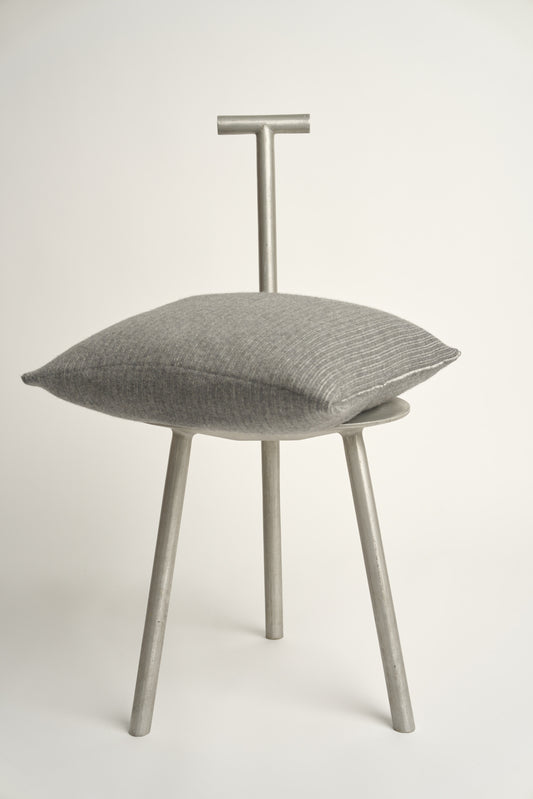 This image displays the Letra Cushion Cover, characterized by its knitted two-tone float knit design. The cushion cover features a textured, cozy appearance in an ivory & slate color, which comes across as modern and stylish.