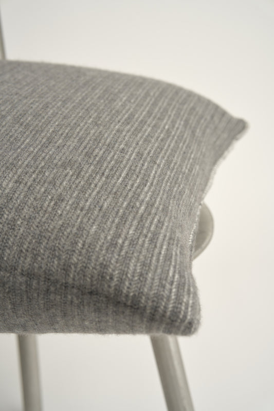 This image displays the Letra Cushion Cover, characterized by its knitted two-tone float knit design. The cushion cover features a textured, cozy appearance in an ivory & slate color, which comes across as modern and stylish.