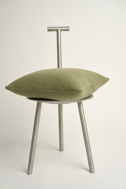 This image displays the Letra Cushion Cover, characterized by its knitted two-tone float knit design. The cushion cover features a textured, cozy appearance in a green & taupe color, which comes across as modern and stylish.