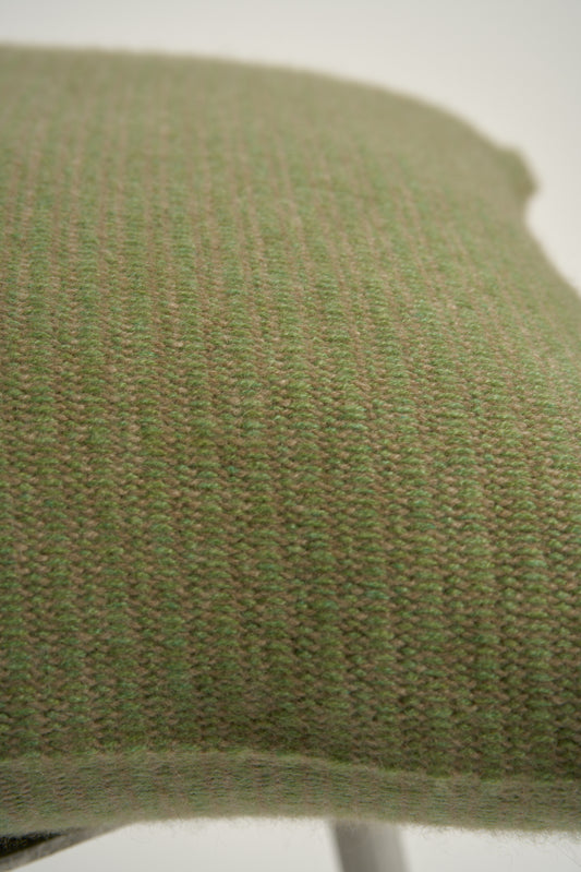 This image displays the Letra Cushion Cover, characterized by its knitted two-tone float knit design. The cushion cover features a textured, cozy appearance in a green & taupe color, which comes across as modern and stylish.