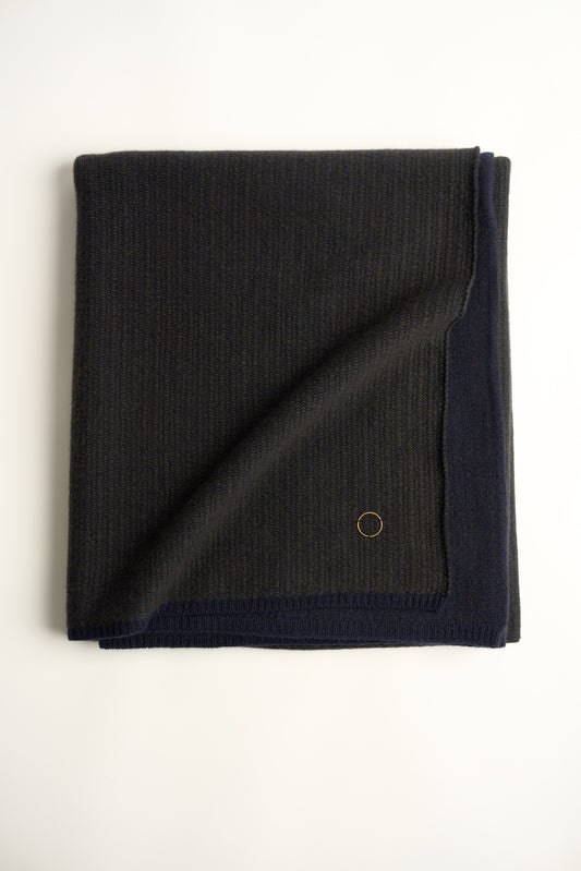 This image features the Letra Throw, a knitted, two-tone float knit throw in a warm, inviting color. The throw displays a soft, textured fabric with a stylish float knit pattern that adds depth and visual interest.