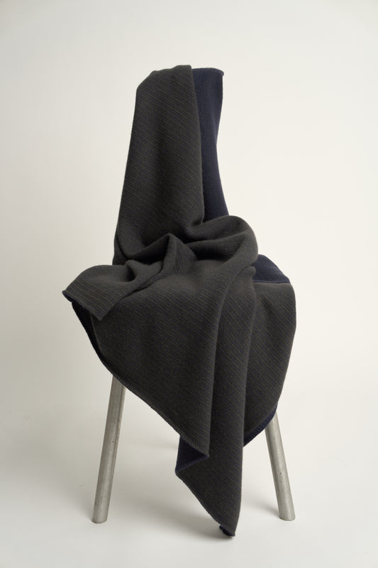 This image features the Letra Throw, a knitted, two-tone float knit throw in a warm, inviting color. The throw displays a soft, textured fabric with a stylish float knit pattern that adds depth and visual interest.