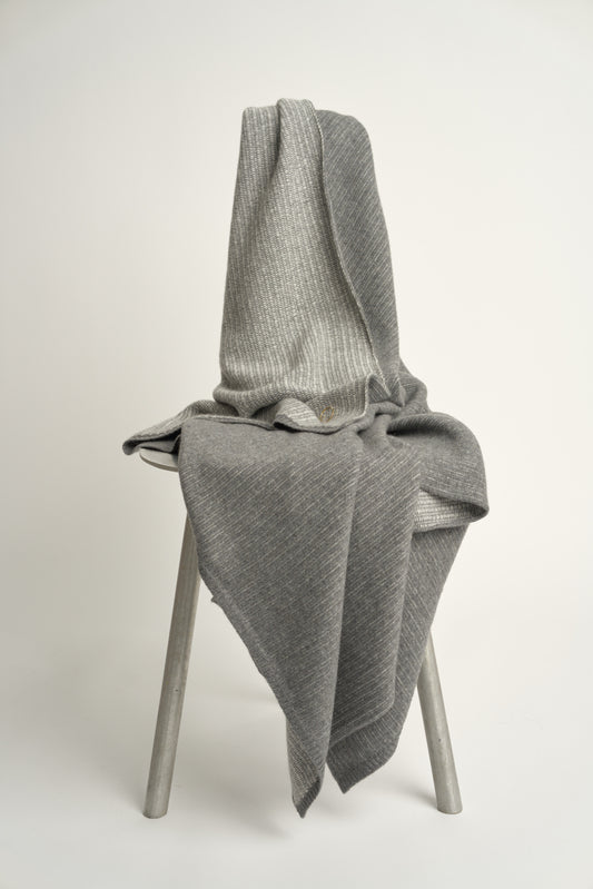 This image features the Letra Throw, a knitted, two-tone float knit throw in a warm, inviting color. The throw displays a soft, textured fabric with a stylish float knit pattern that adds depth and visual interest.