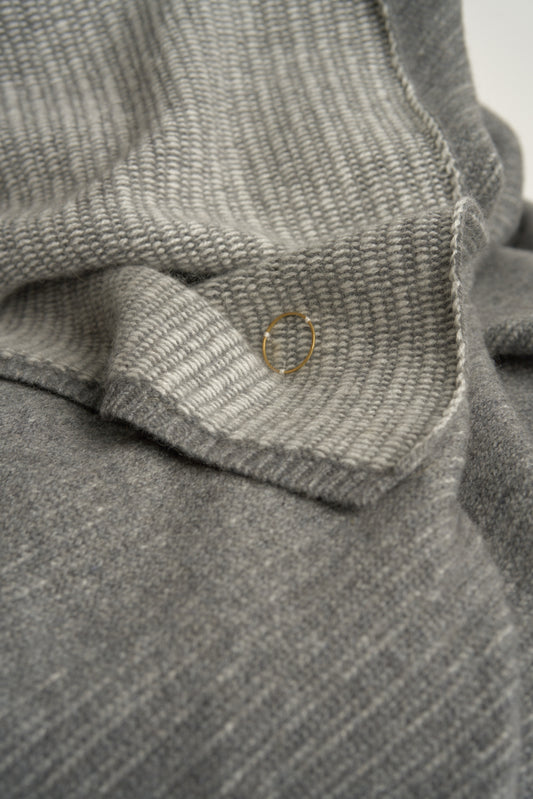 This image features the Letra Throw, a knitted, two-tone float knit throw in a warm, inviting color. The throw displays a soft, textured fabric with a stylish float knit pattern that adds depth and visual interest.