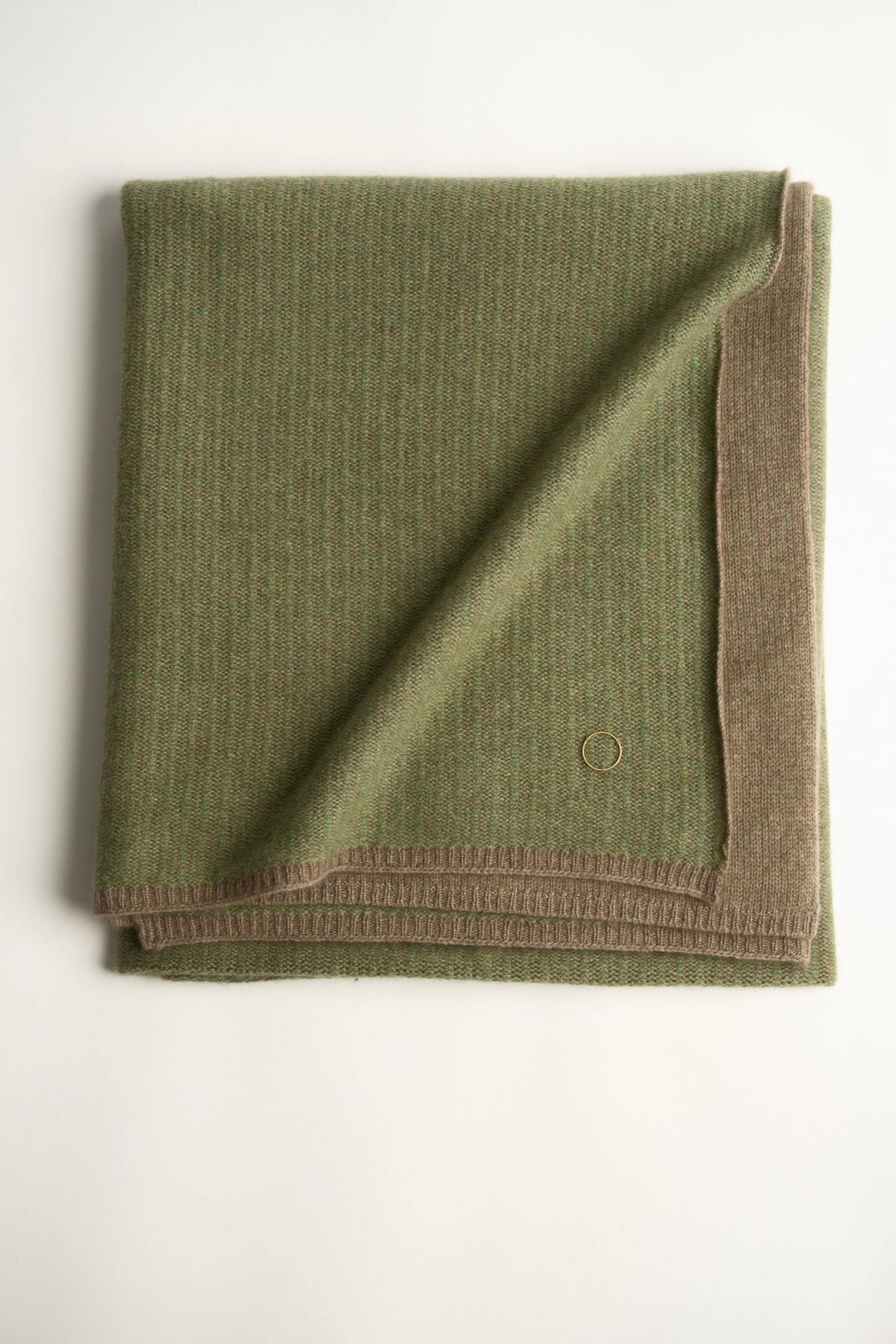 This image features the Letra Throw, a knitted, two-tone float knit throw in a warm, inviting color. The throw displays a soft, textured fabric with a stylish float knit pattern that adds depth and visual interest.