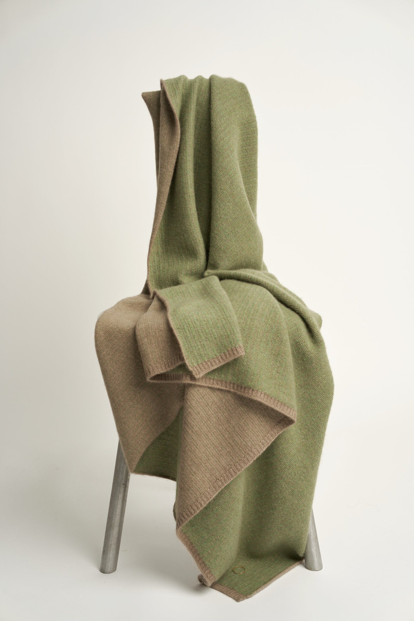 This image features the Letra Throw, a knitted, two-tone float knit throw in a warm, inviting color. The throw displays a soft, textured fabric with a stylish float knit pattern that adds depth and visual interest.