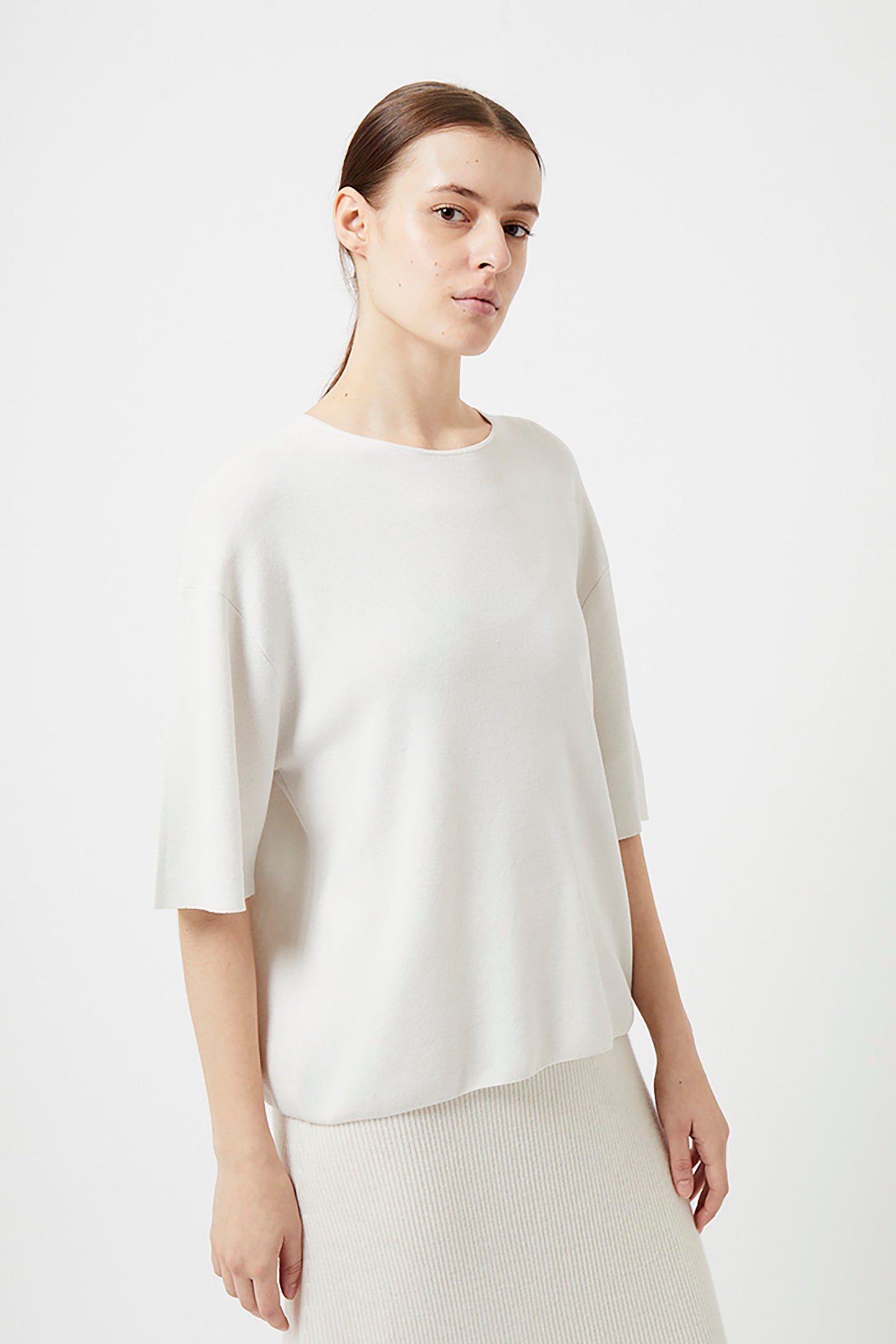 Woman wearing an ivory top against a plain background