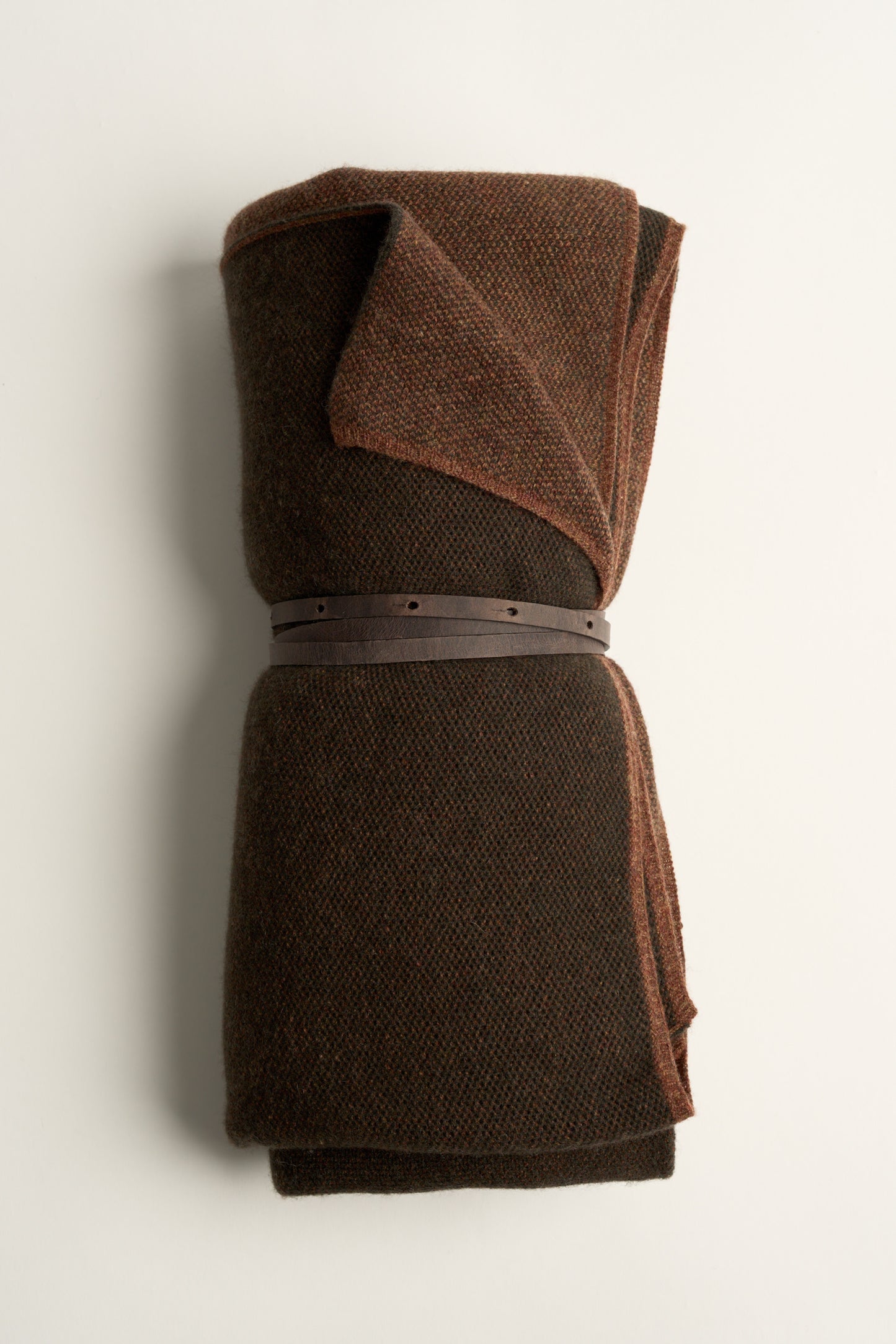 This image displays the Mandu Travel Throw, a luxuriously soft and stylish accessory perfect for enhancing any space. The throw features a delicate, knitted texture in a dual-tone color scheme, with shades of dark brown and subtle beige.