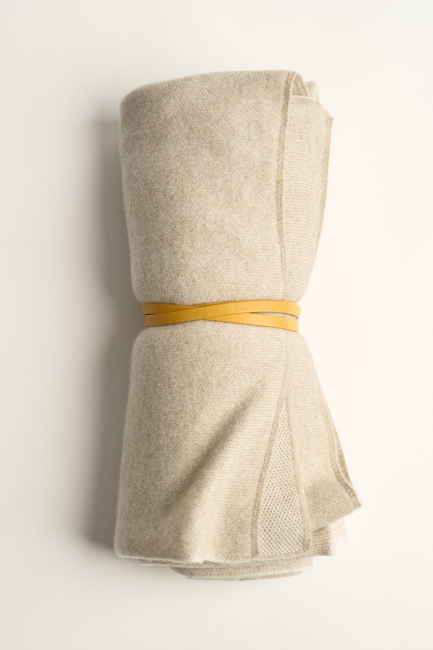 This image displays the Mandu Travel Throw, a luxuriously soft and stylish accessory perfect for enhancing any space. The throw features a delicate, knitted texture in a dual-tone color scheme, with shades of subtle beige.