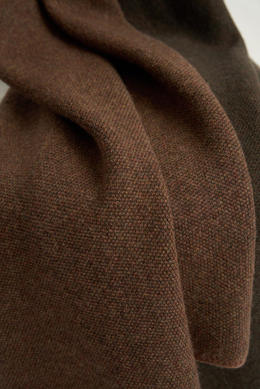 This image features the Mandu Throw, a knitted microfiber throw in a two-tone brown color. The throw displays a soft, textured surface with subtle striping details, enhancing its stylish and cozy appearance.