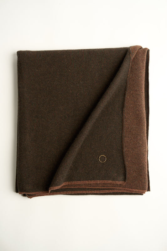 This image features the Mandu Throw, a knitted microfiber throw in a two-tone brown color. The throw displays a soft, textured surface with subtle striping details, enhancing its stylish and cozy appearance.
