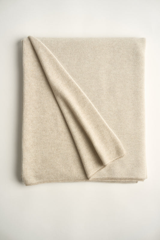 This image features the Mandu Throw, a knitted microfiber throw in a two-tone feather & ivory color. The throw displays a soft, textured surface with subtle striping details, enhancing its stylish and cozy appearance.