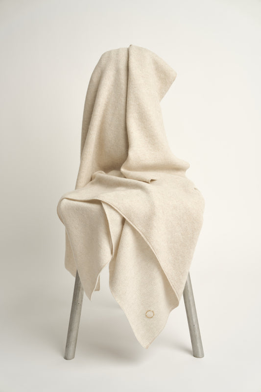 This image features the Mandu Throw, a knitted microfiber throw in a two-tone feather & ivory color. The throw displays a soft, textured surface with subtle striping details, enhancing its stylish and cozy appearance.