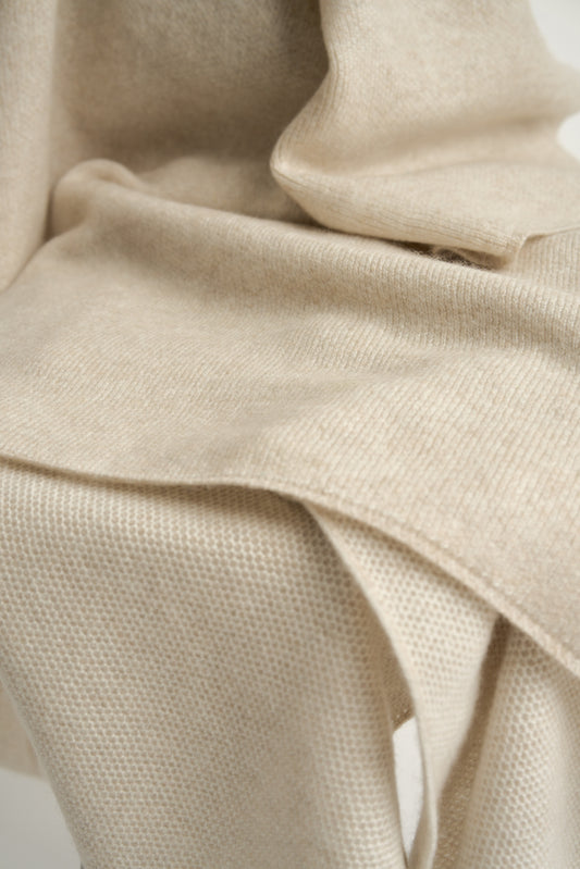 This image features the Mandu Throw, a knitted microfiber throw in a two-tone feather & ivory color. The throw displays a soft, textured surface with subtle striping details, enhancing its stylish and cozy appearance.