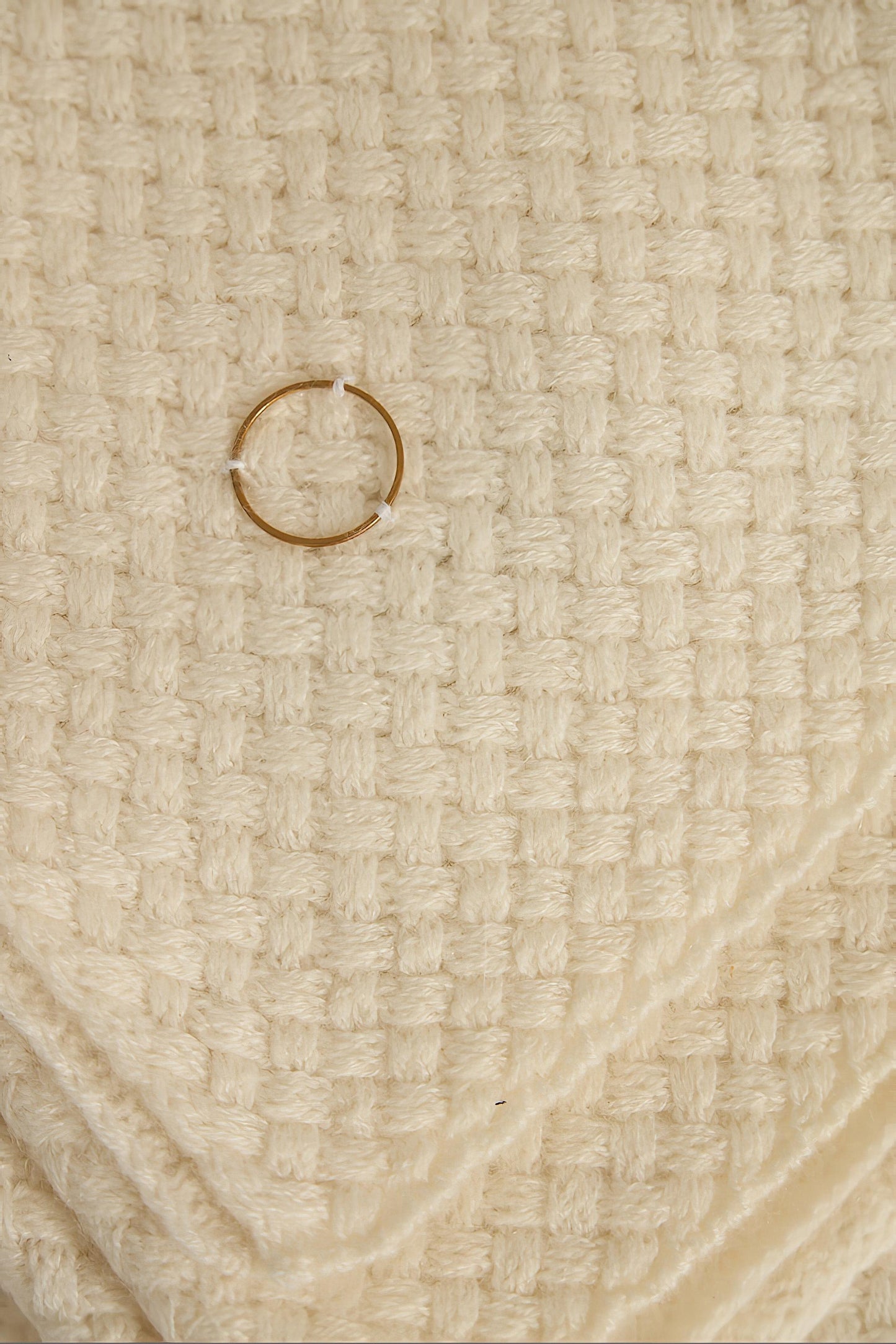 An ivory cashmere bedspread with a subtle pattern, displayed on a neutral background.