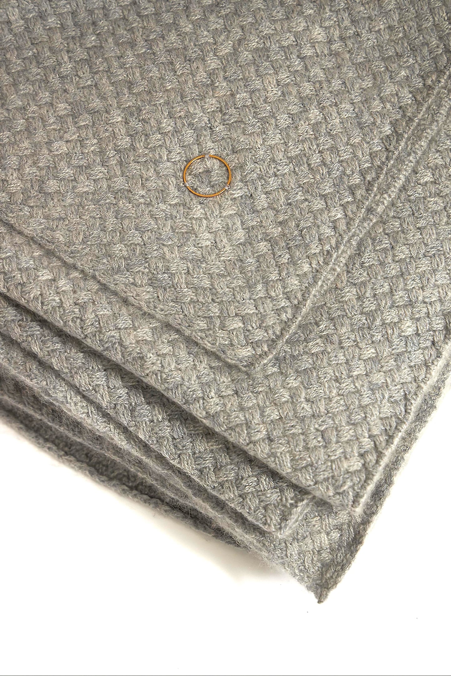 A soft grey cashmere bedspread with a subtle pattern, displayed on a neutral background.