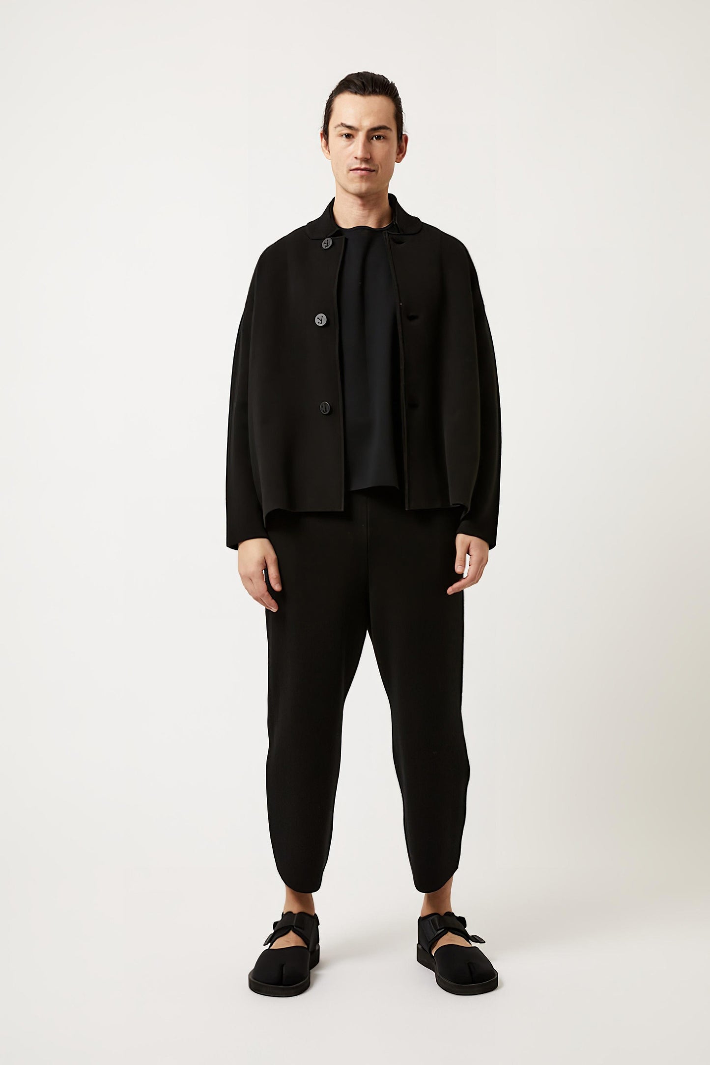 This image features a model wearing the Wind Jacket from Oyuna's core collection. The jacket is designed with a relaxed-fit and showcases a sophisticated look with its stand-up collar and welt pockets.
