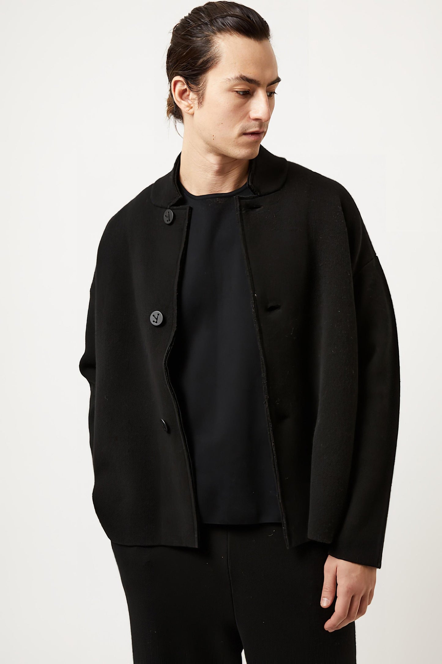 This image features a model wearing the Wind Jacket from Oyuna's core collection. The jacket is designed with a relaxed-fit and showcases a sophisticated look with its stand-up collar and welt pockets.