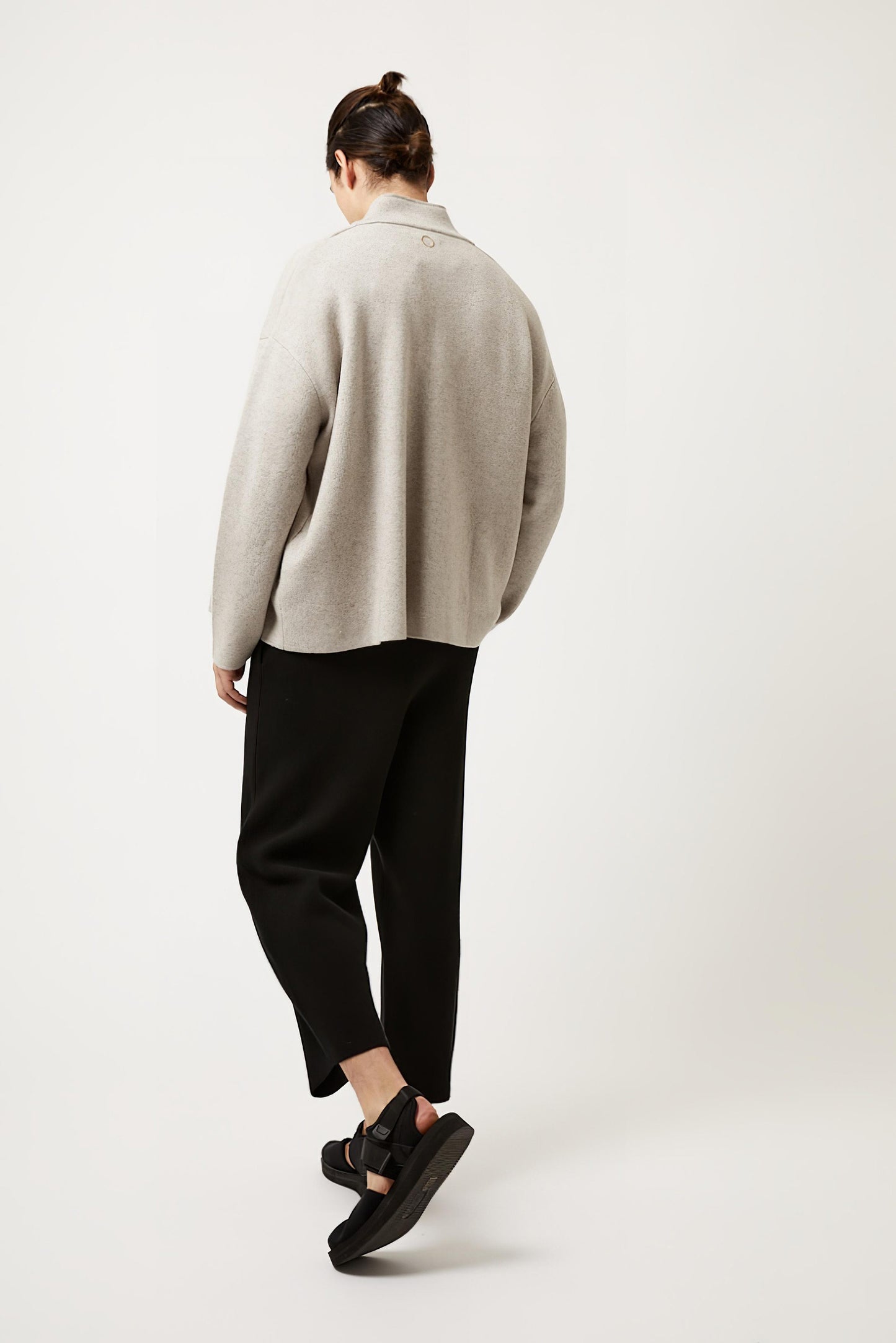 This image features a model wearing the Wind Jacket from Oyuna's core collection. The jacket is designed with a relaxed-fit and showcases a sophisticated look with its stand-up collar and welt pockets.