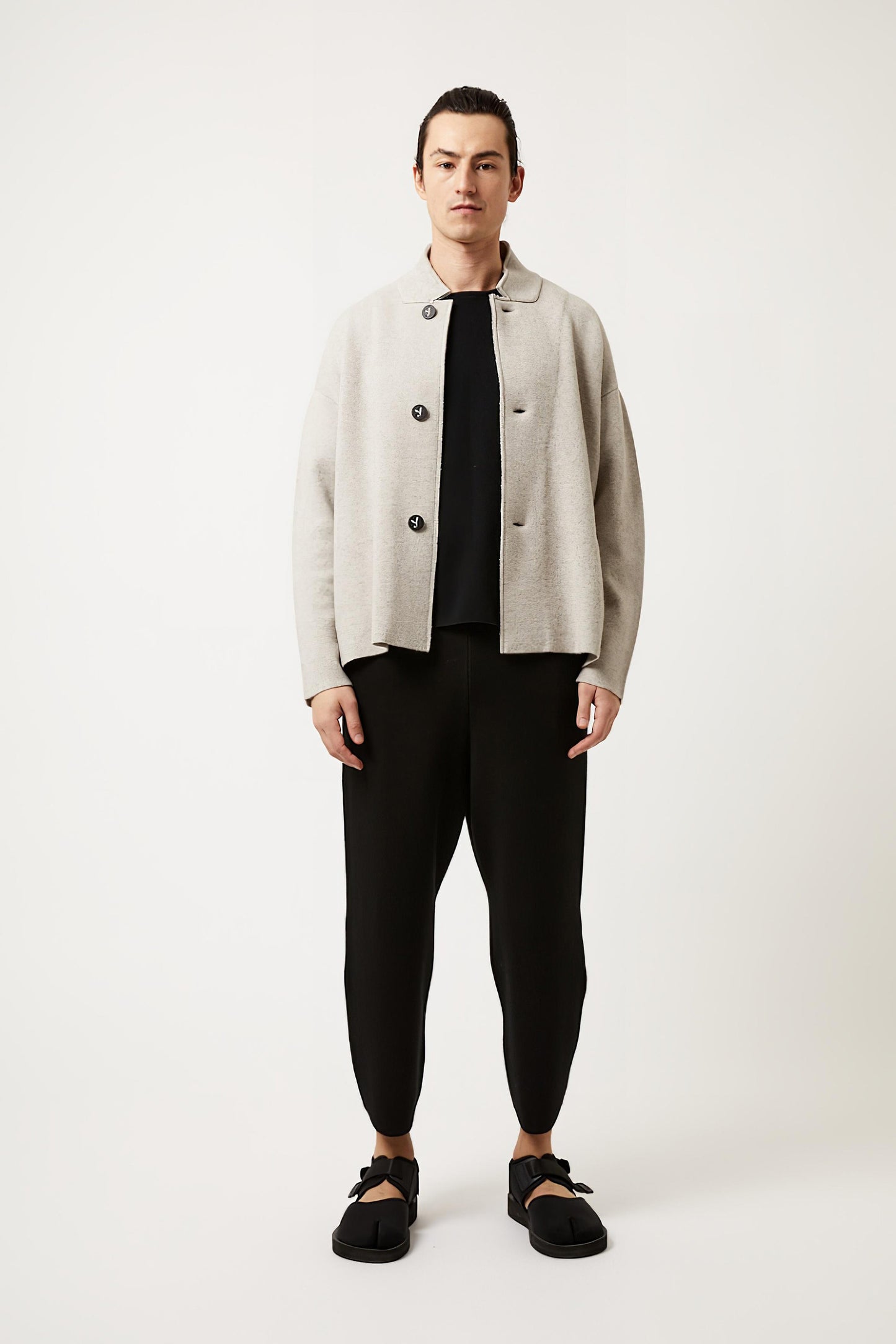 This image features a model wearing the Wind Jacket from Oyuna's core collection. The jacket is designed with a relaxed-fit and showcases a sophisticated look with its stand-up collar and welt pockets.