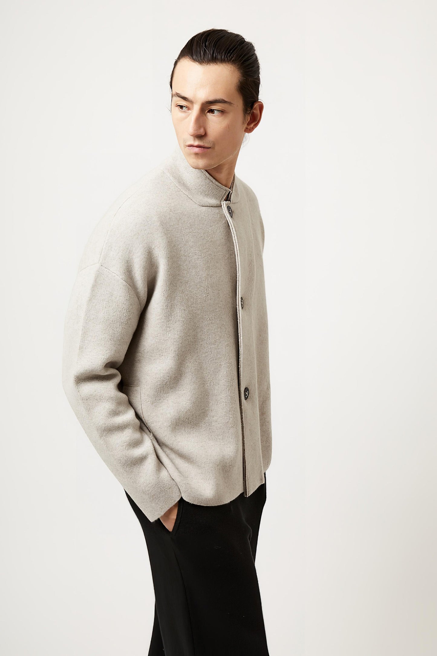 This image features a model wearing the Wind Jacket from Oyuna's core collection. The jacket is designed with a relaxed-fit and showcases a sophisticated look with its stand-up collar and welt pockets.
