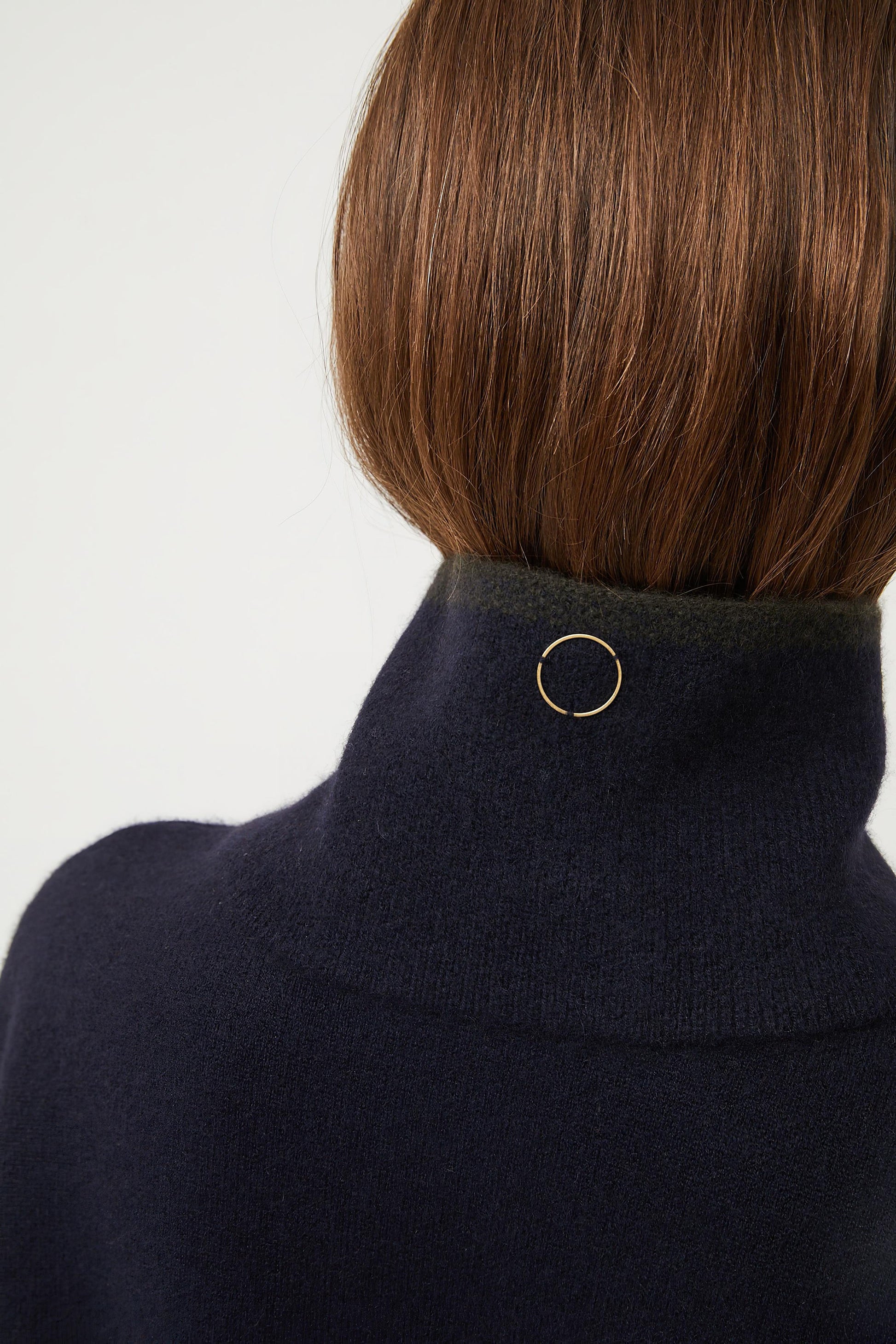 A person wearing an ocean-colored neck snood with a circle detail at the neckline.