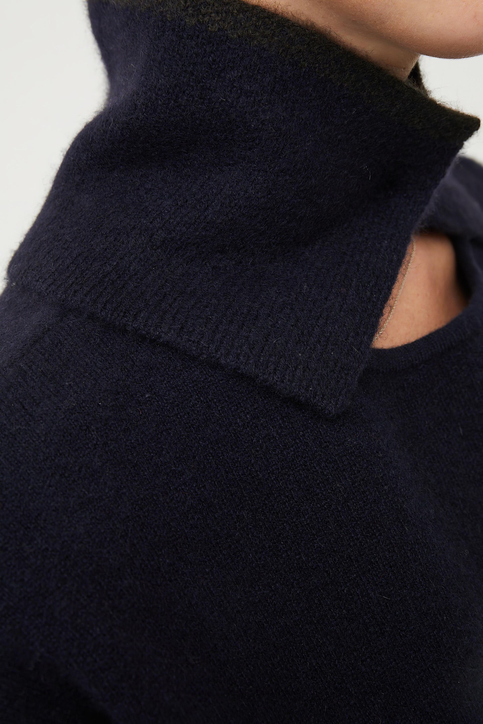 A person wearing an ocean-colored neck snood with a circle detail at the neckline.